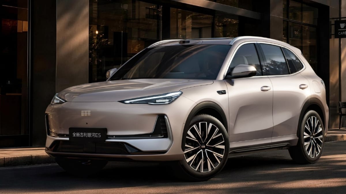 Die Neuauflage des Geely E5 in Champagner steht vor einem Café, auf dem Dach sitzt ein LiDAR-Sensor